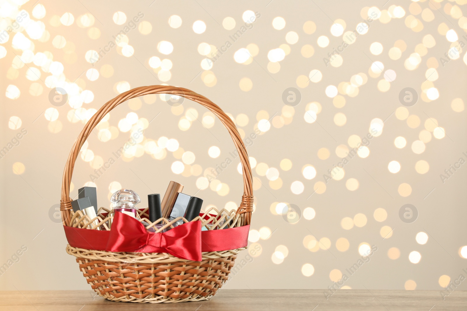 Photo of Wicker basket with cosmetics as present against blurred festive lights. Space for text