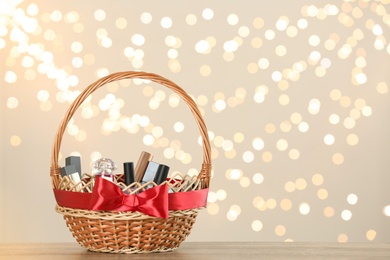 Photo of Wicker basket with cosmetics as present against blurred festive lights. Space for text