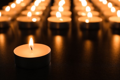 Wax candle burning on table in darkness, closeup