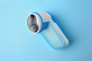 Modern fabric shaver on light blue background, top view