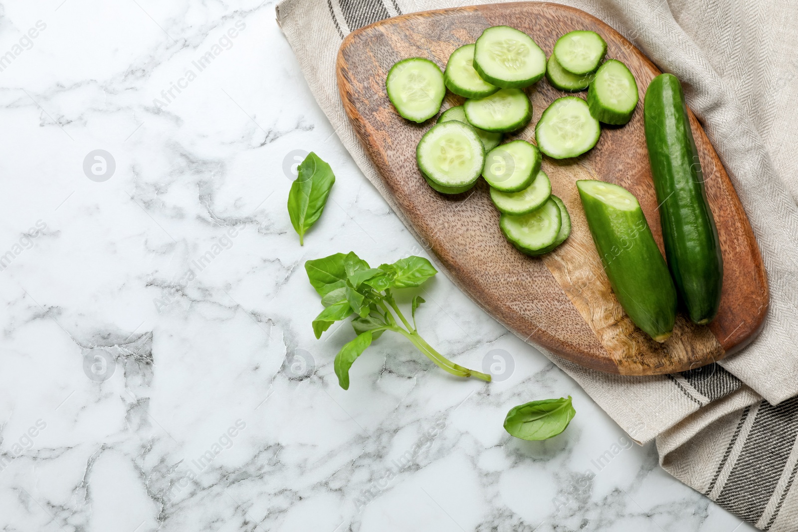 Photo of Fresh ripe cucumbers and basil on white marble table, flat lay. Space for text