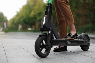 Photo of Businesswoman with modern electric kick scooter on city street, closeup. Space for text