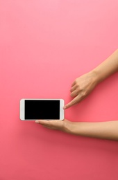 Photo of Woman holding modern phone on pink background, top view. Space for text