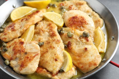 Photo of Delicious chicken piccata with lemons on grey table, closeup