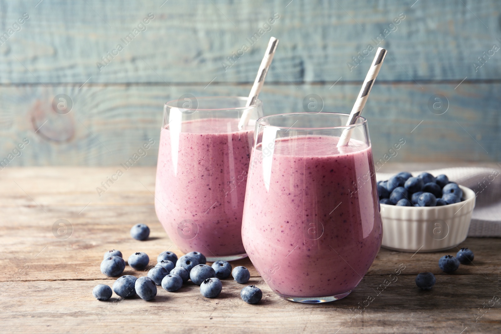 Photo of Tasty blueberry smoothie in glasses and berries on wooden table