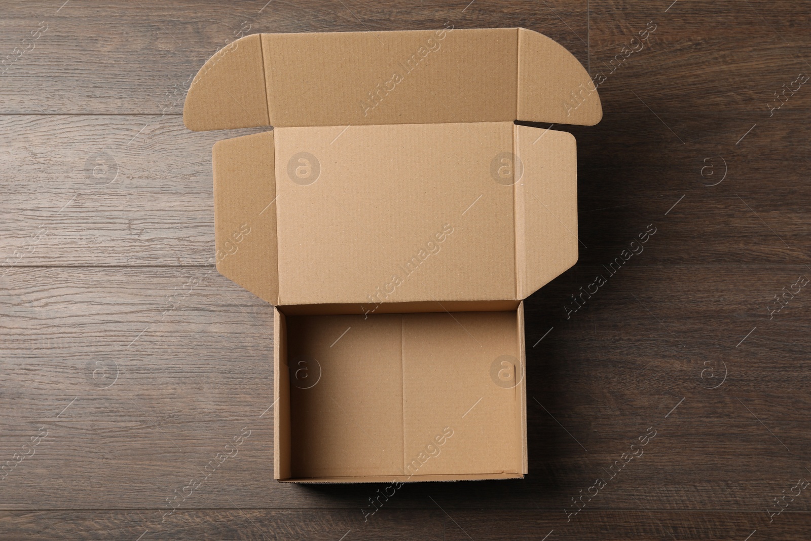Photo of Empty open cardboard box on wooden table, top view