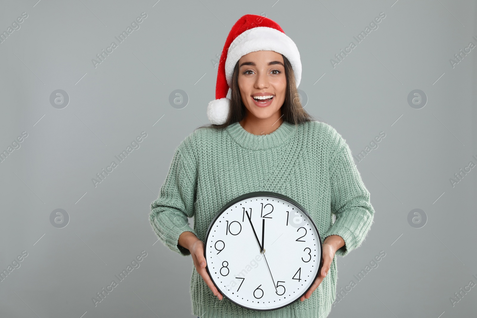 Photo of Woman in Santa hat with clock on grey background. Christmas countdown