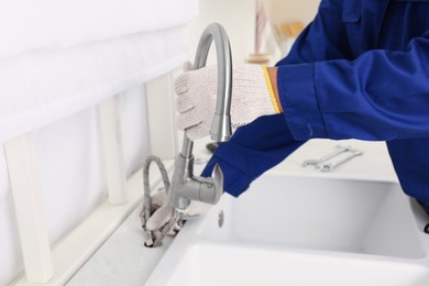 Photo of Plumber repairing water tap in kitchen, closeup