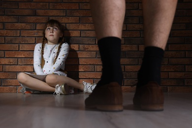 Photo of Adult man without pants standing in front of scared little girl indoors. Child in danger