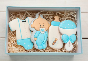 Set of baby shower cookies in gift box on white wooden table, top view