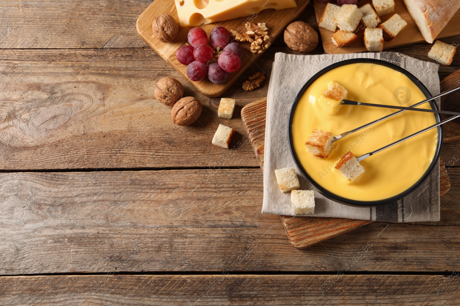 Photo of Tasty cheese fondue and snacks on wooden table, flat lay. Space for text