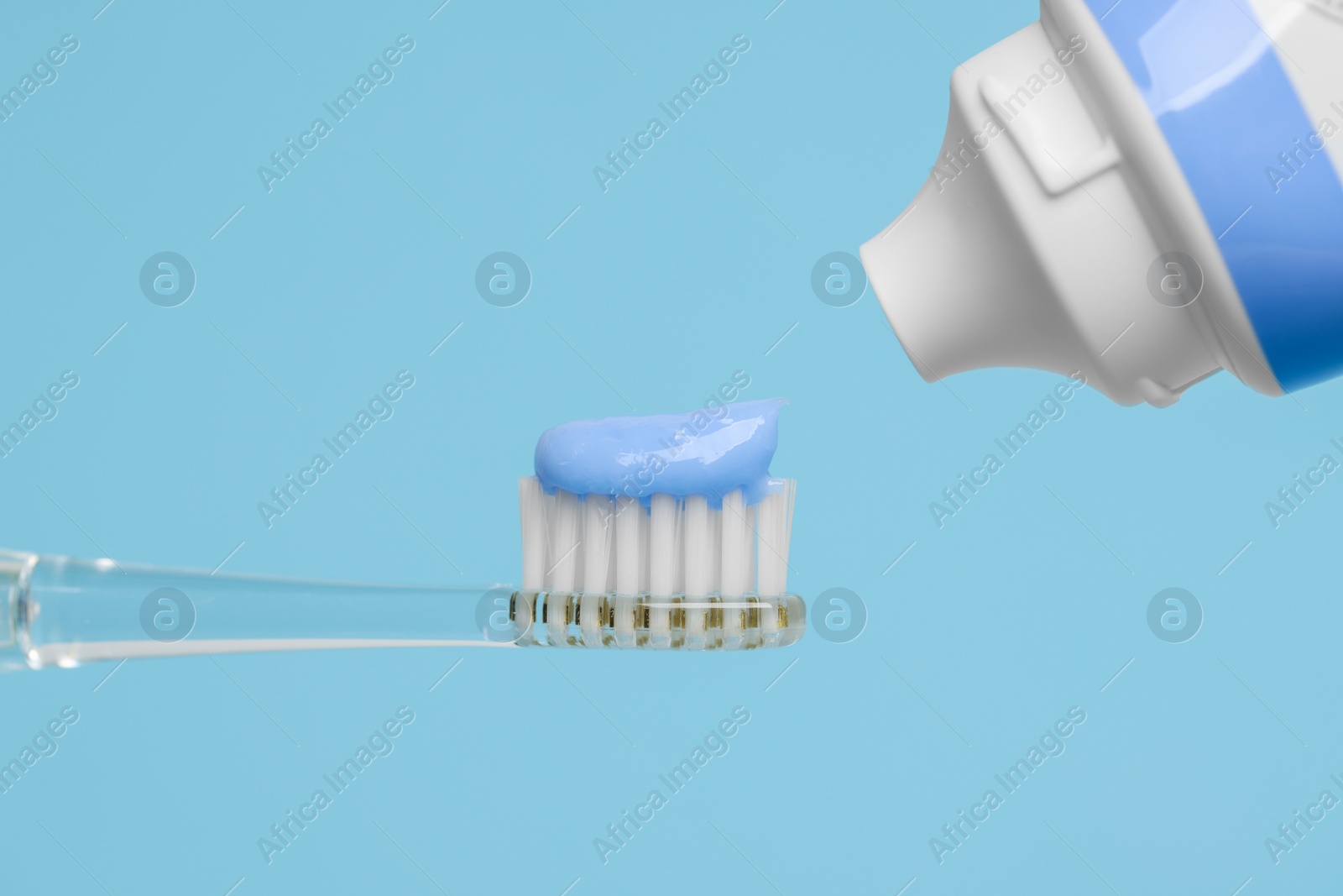 Photo of Electric toothbrush with paste on light blue background, closeup