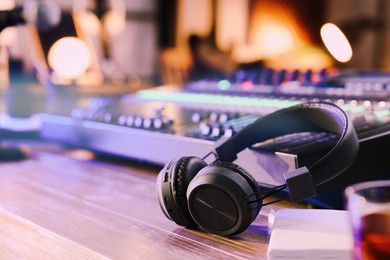 Headphones and professional mixing console on table in radio studio