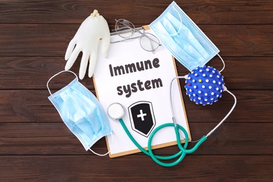 Clipboard with phrase Immune System and medical items on wooden table, flat lay