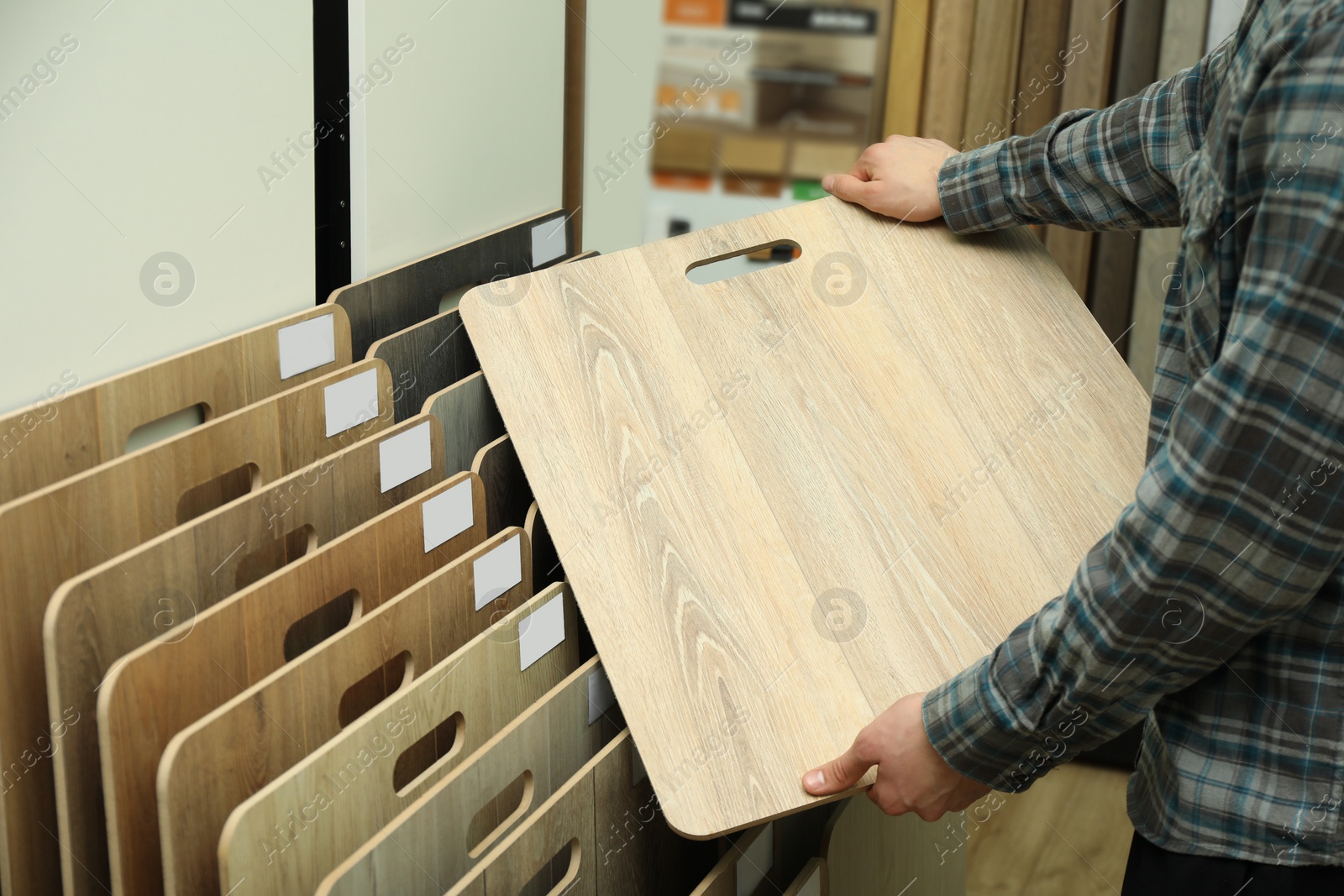 Photo of Man with sample of wooden flooring in shop, closeup