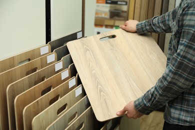 Photo of Man with sample of wooden flooring in shop, closeup