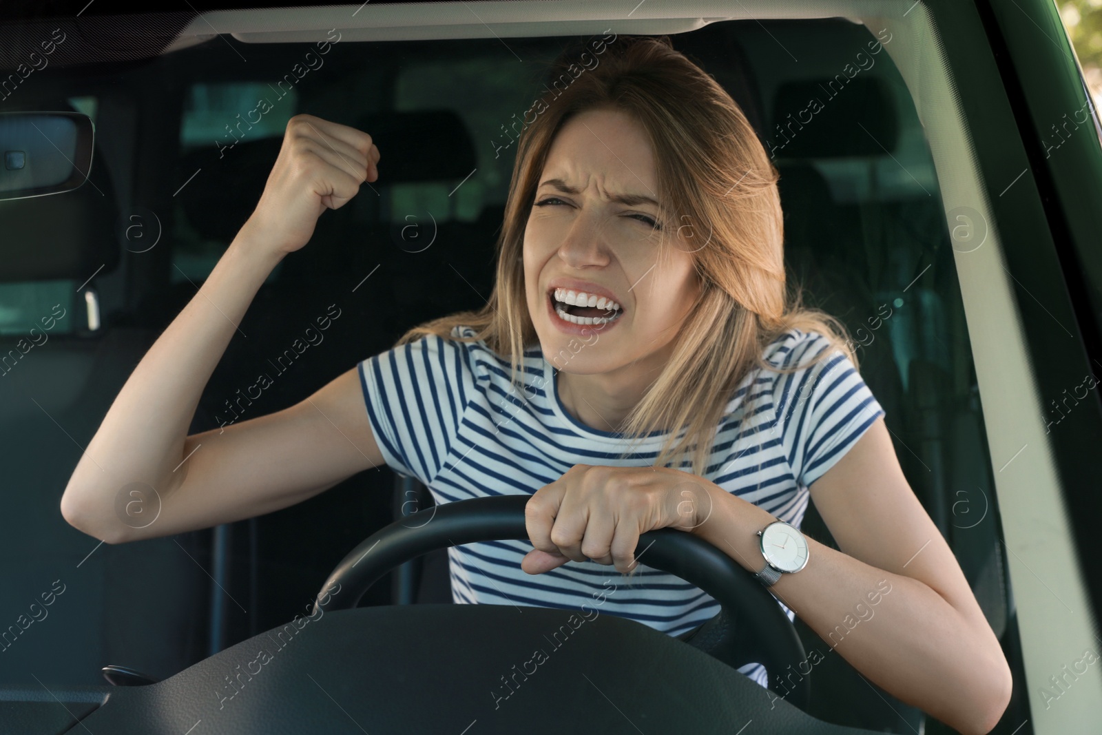 Photo of Stressed angry woman in driver's seat of modern car, view through windshield