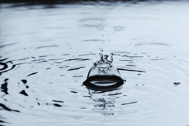 Photo of Rain drops falling down into puddle outdoors