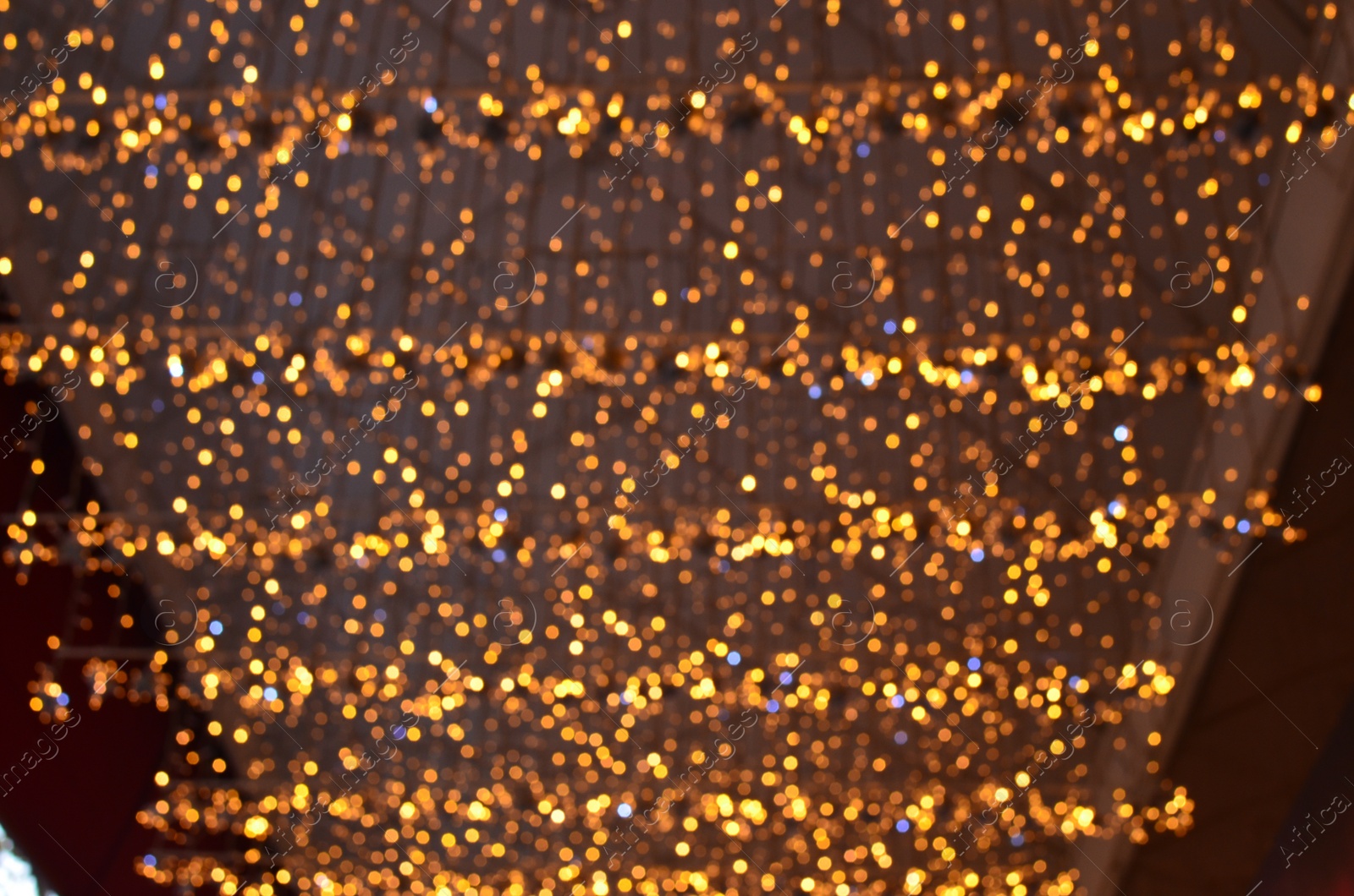 Photo of Blurred view of beautiful lights hanging from ceiling indoors. Bokeh effect