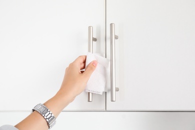 Photo of Woman using tissue paper to open cabinet door, closeup