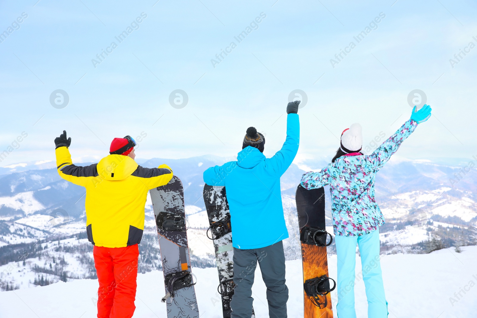 Photo of Friends with snowboards at mountain resort, back view. Winter vacation