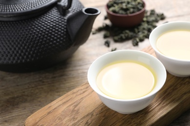 Photo of Cups and teapot of Tie Guan Yin oolong on wooden table. Space for text