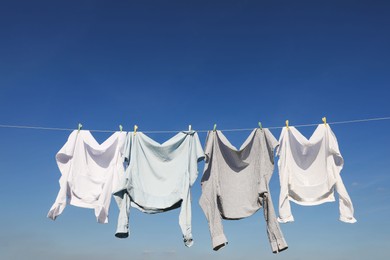 Photo of Washing line with drying clothes and clothespins under blue sky, space for text