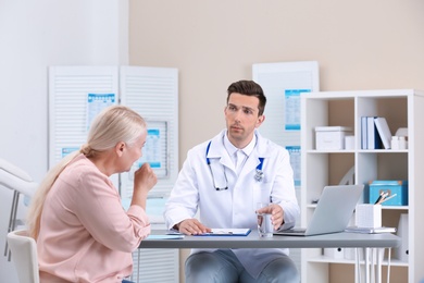 Photo of Coughing mature woman visiting doctor at clinic