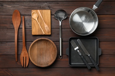 Set of modern cooking utensils on brown wooden table, flat lay