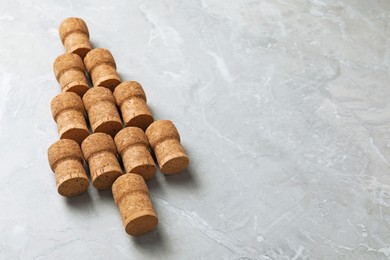 Photo of Christmas tree made of wine corks on light grey table. Space for text