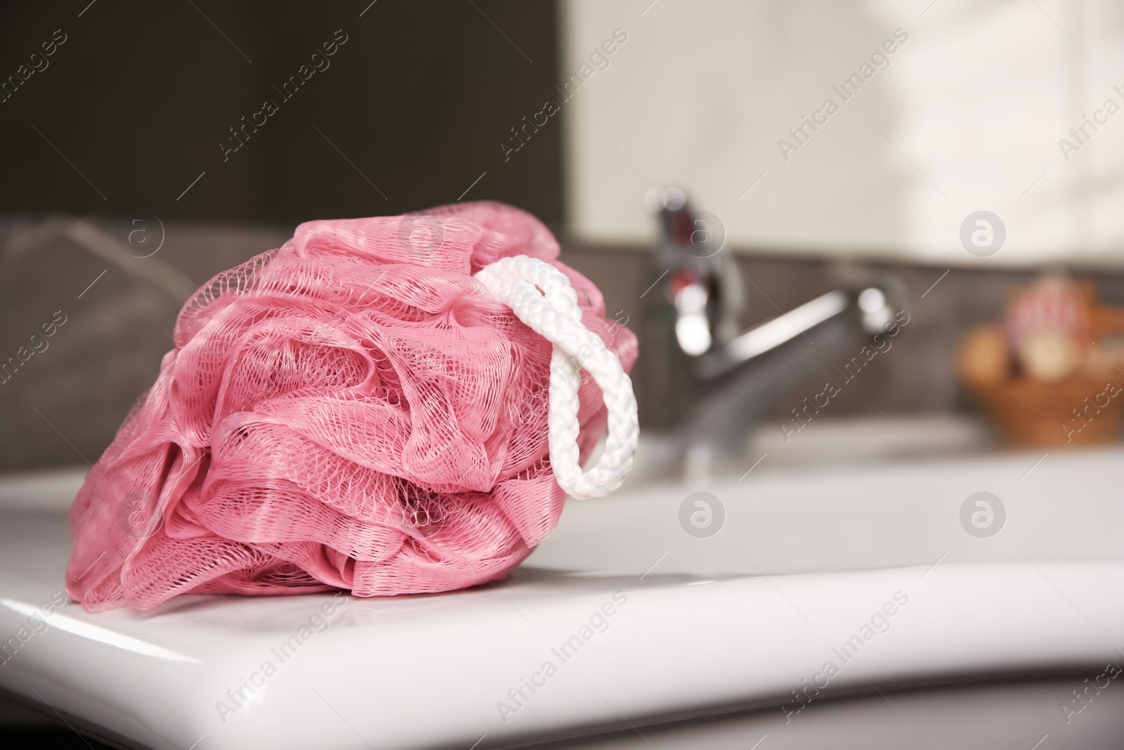 Photo of Pink shower puff on washbasin in bathroom, closeup. Space for text