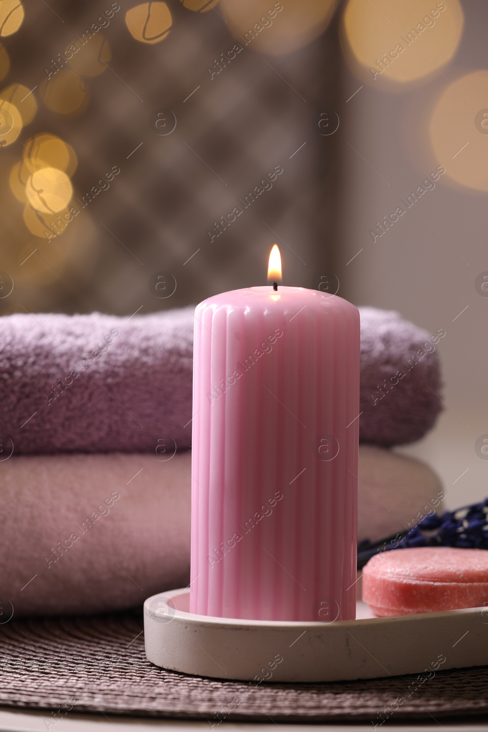 Photo of Spa composition. Burning candle, towels and soap on table