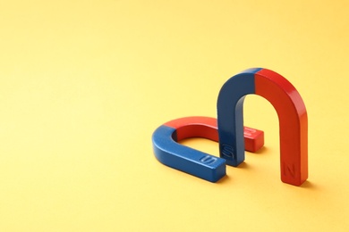 Photo of Red and blue horseshoe magnets on color background. Space for text