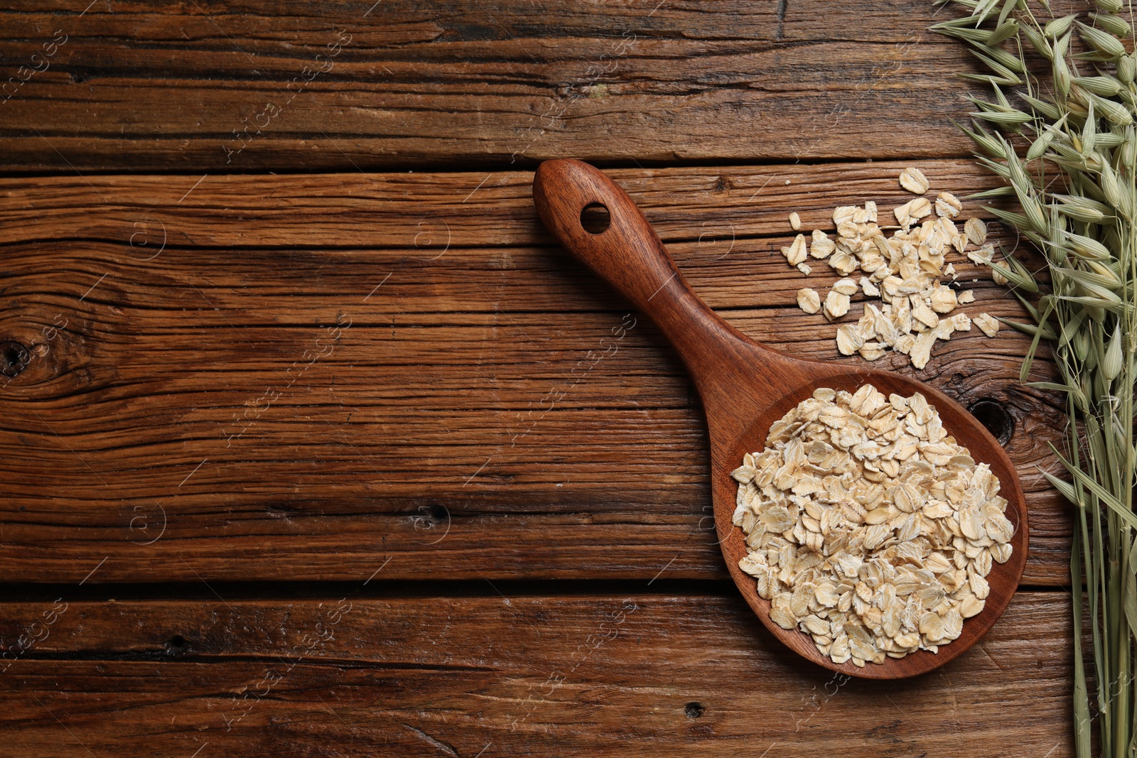 Photo of Spoon with oatmeal and floret branches on wooden table, flat lay. Space for text