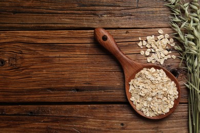 Spoon with oatmeal and floret branches on wooden table, flat lay. Space for text