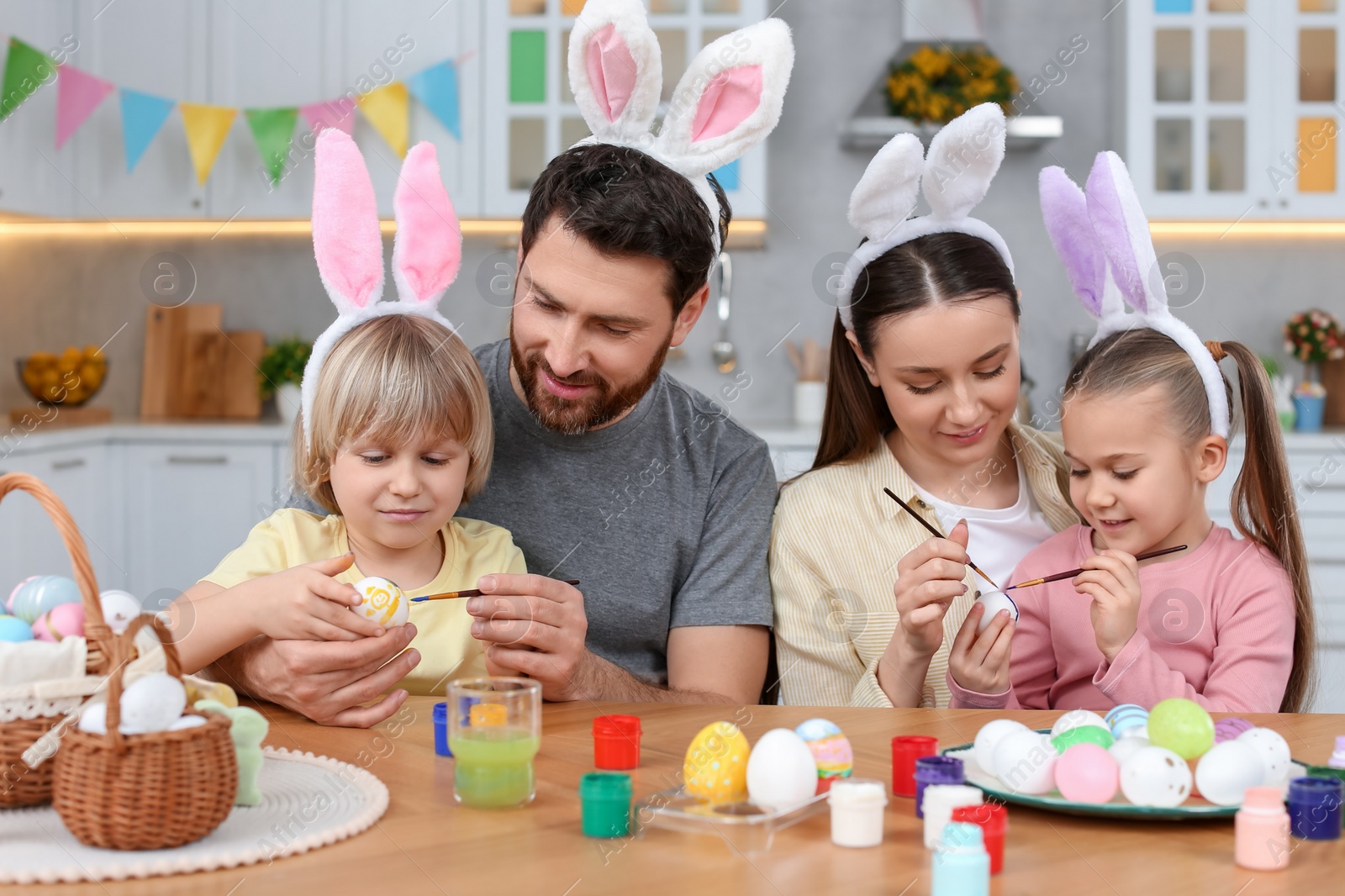 Photo of Happy family painting Easter eggs at table in kitchen