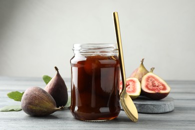 Photo of Jar of tasty sweet jam and fresh figs on grey table