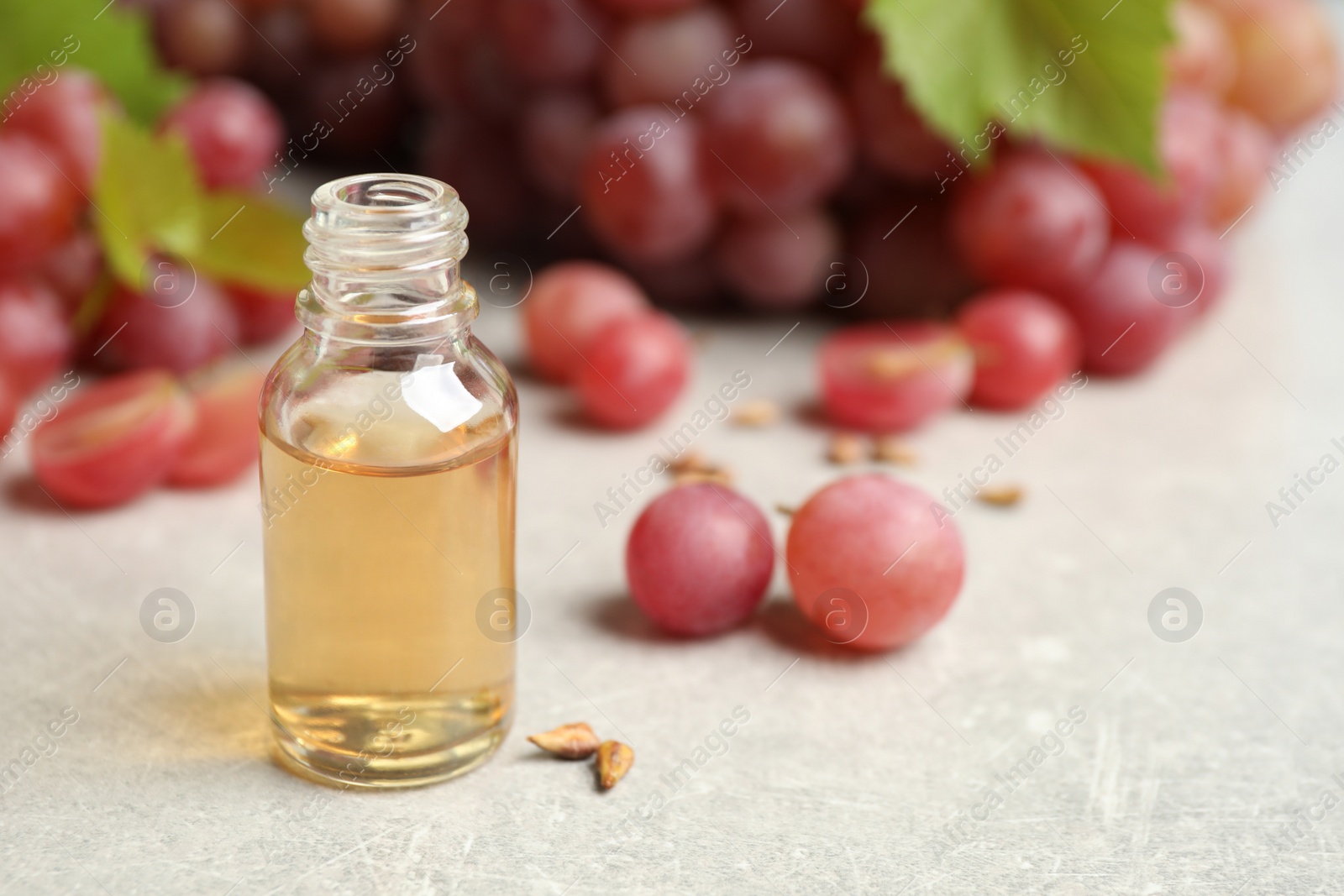 Photo of Natural grape seed oil and fresh berries on light table, space for text. Organic cosmetic