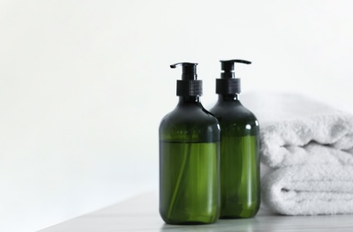 Photo of Soap dispensers and clean towels on white table. Space for text