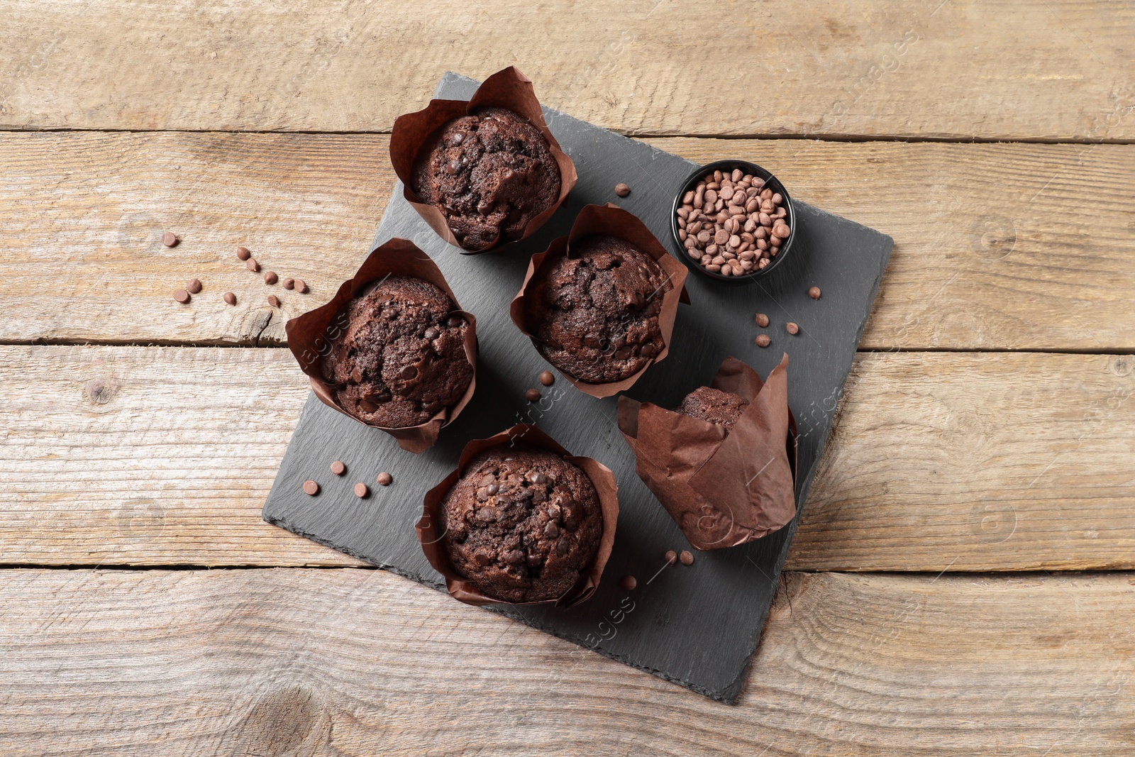 Photo of Delicious chocolate muffins on wooden table, top view