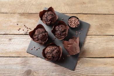 Delicious chocolate muffins on wooden table, top view