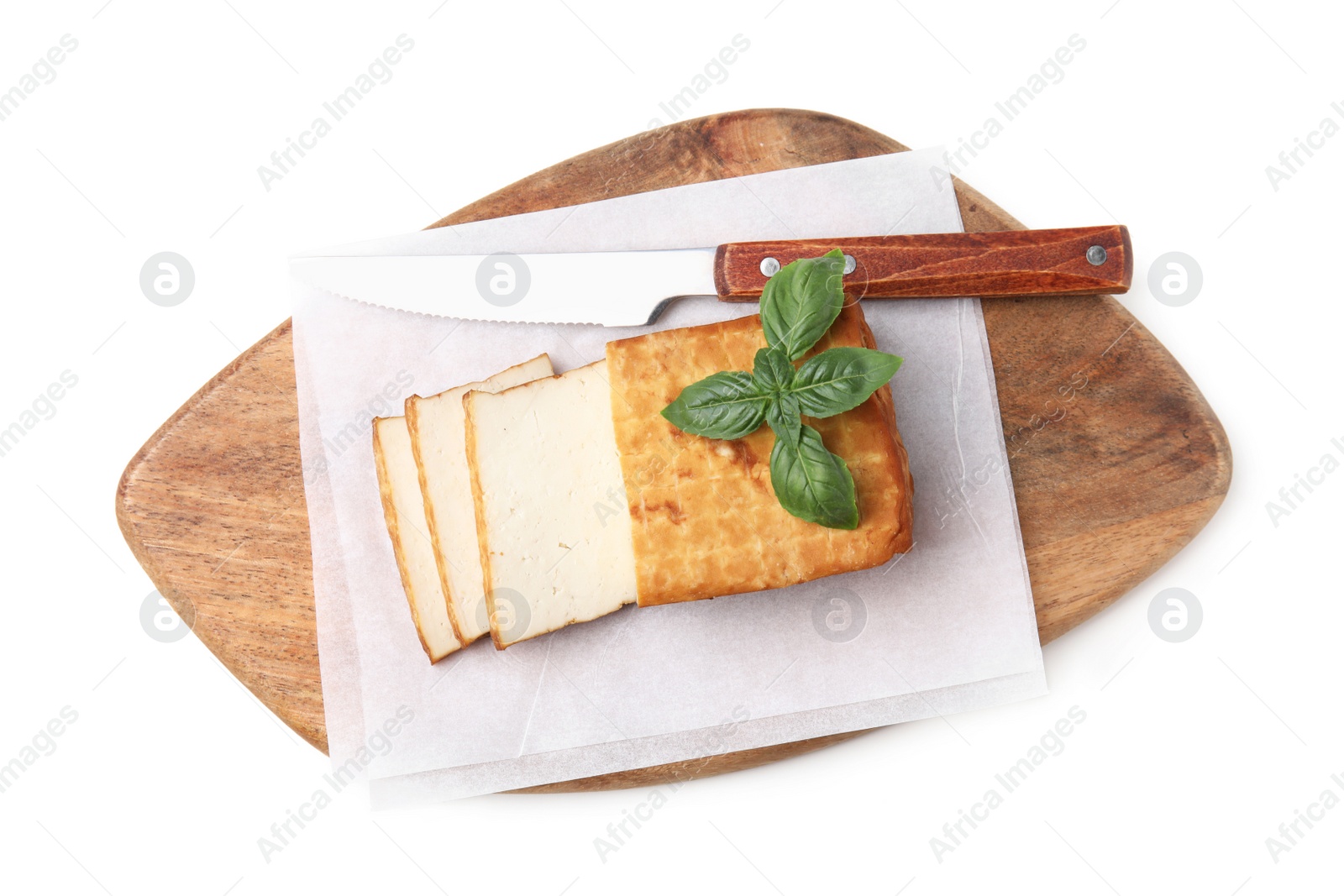 Photo of Wooden board with smoked tofu, knife and basil on white background, top view