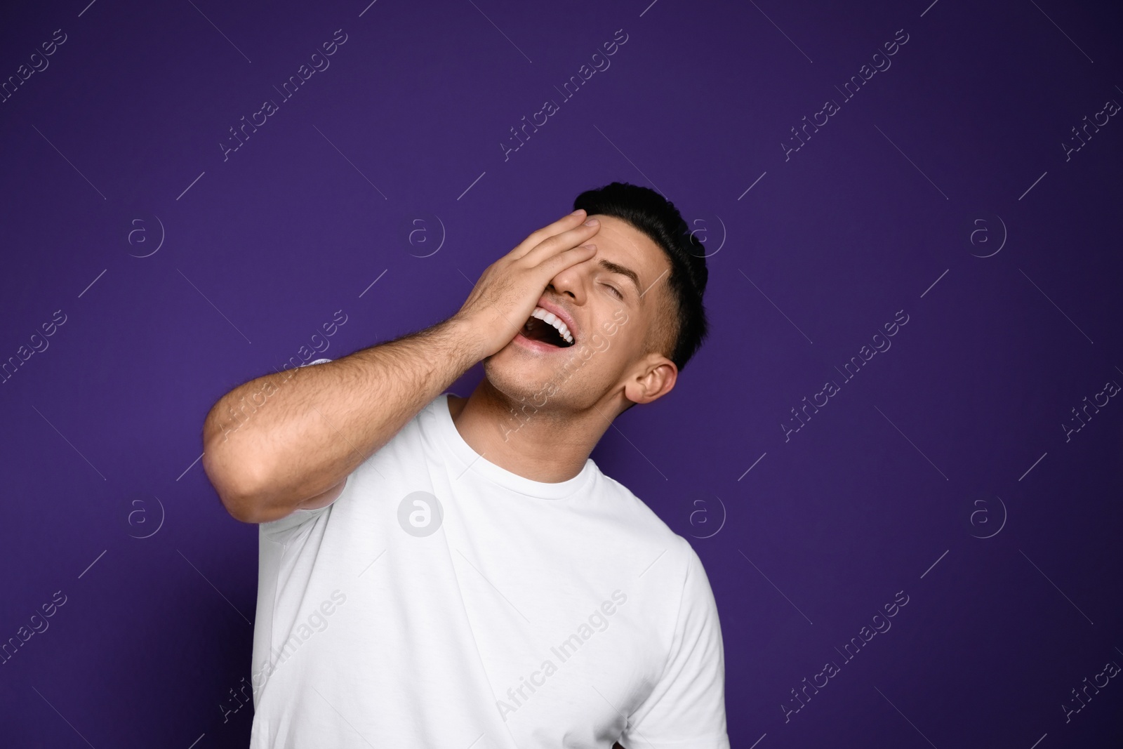 Photo of Handsome man laughing on purple background. Funny joke