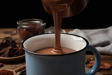 Pouring yummy hot chocolate into mug on table, closeup
