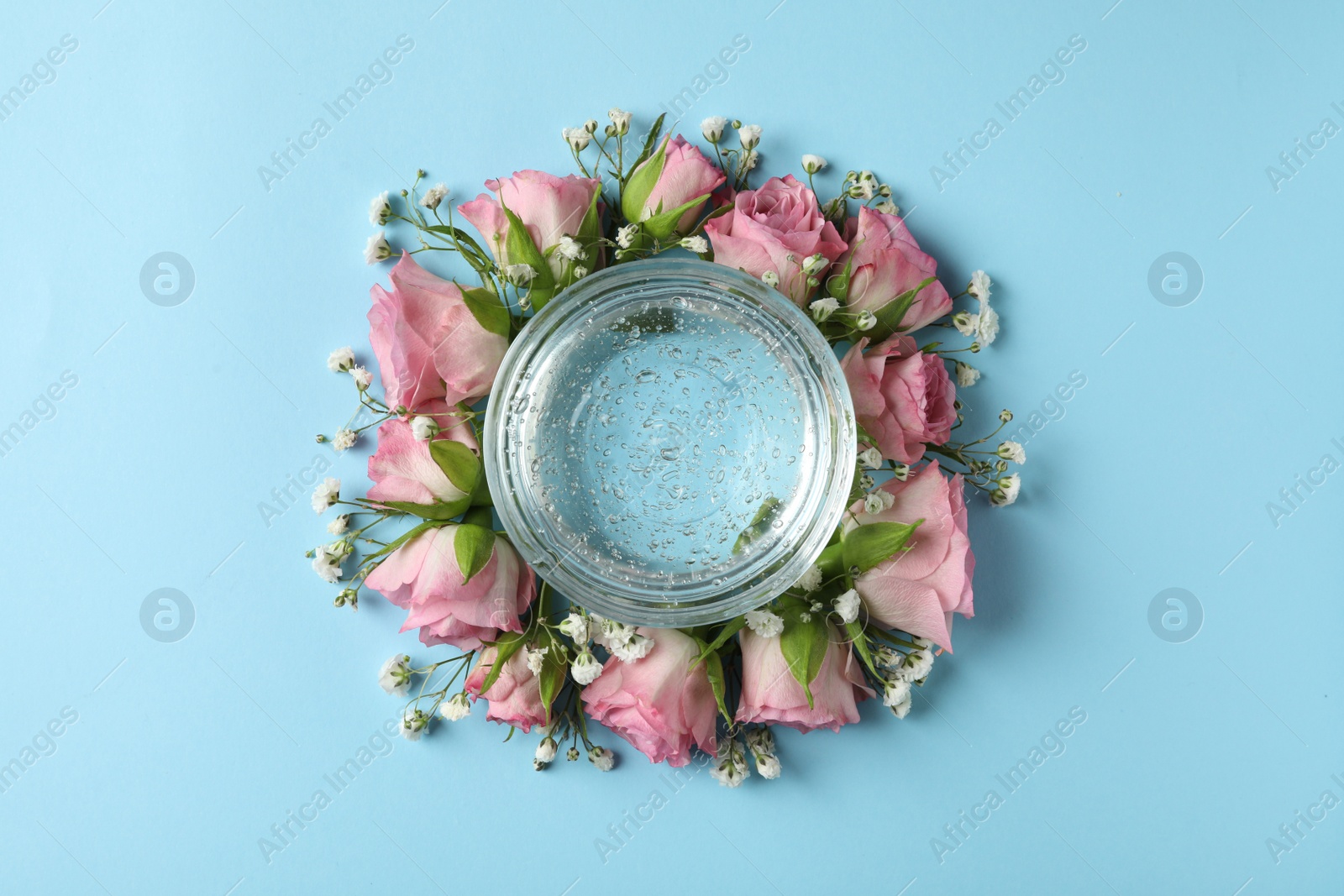 Photo of Flat lay composition with cosmetic gel and beautiful flowers on light blue background