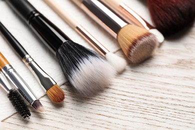 Clean makeup brushes with napkin on wooden table, closeup