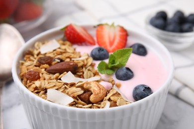 Photo of Tasty granola, yogurt and fresh berries in bowl on table, closeup. Healthy breakfast