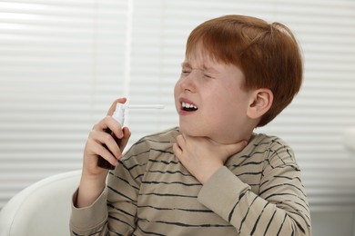 Little boy using throat spray at home