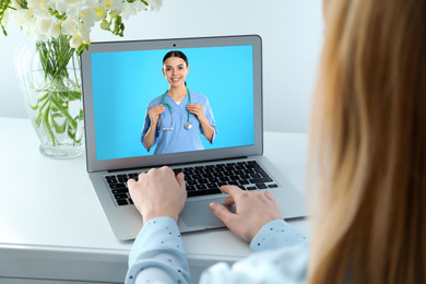 Image of Woman using laptop at table for online consultation with doctor via video chat, closeup