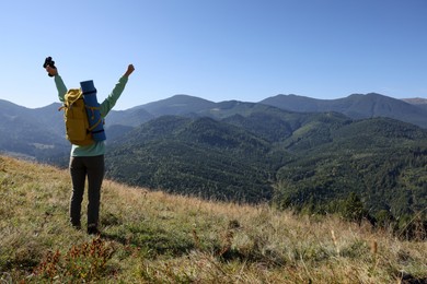 Photo of Happy tourist with backpack and binoculars in mountains on sunny day, back view